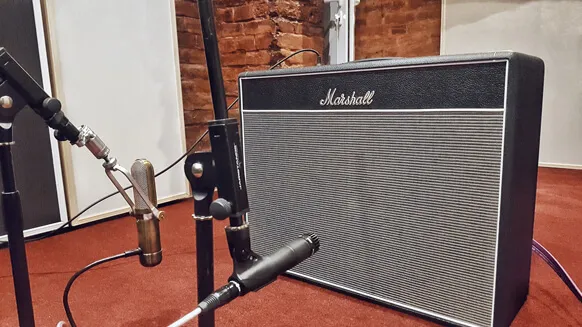 A Marshall guitar amp with microphones in front of it