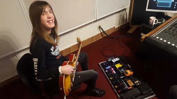 A guitarist recording with a pedalboard