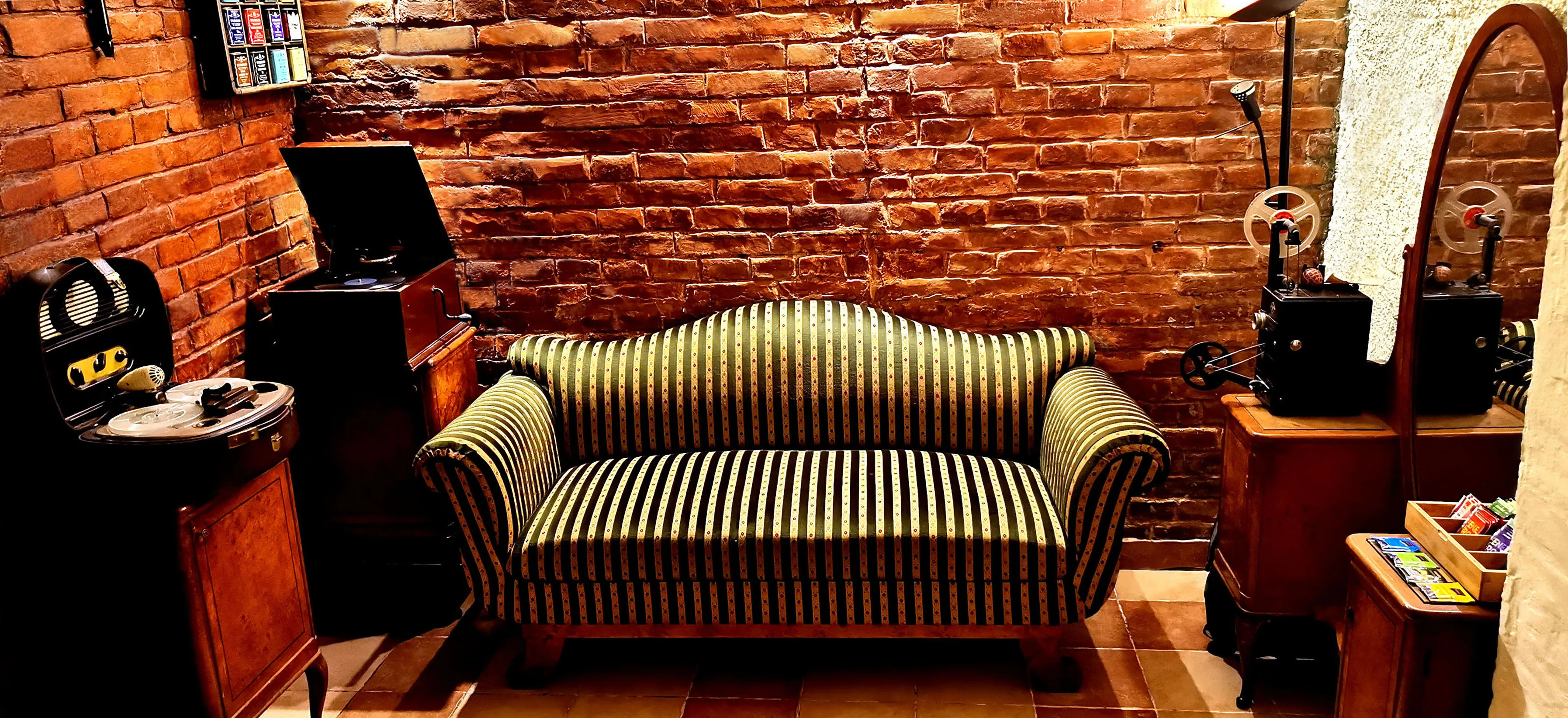 The lounge with a 19th century sofa, a gramophone and red brick walls