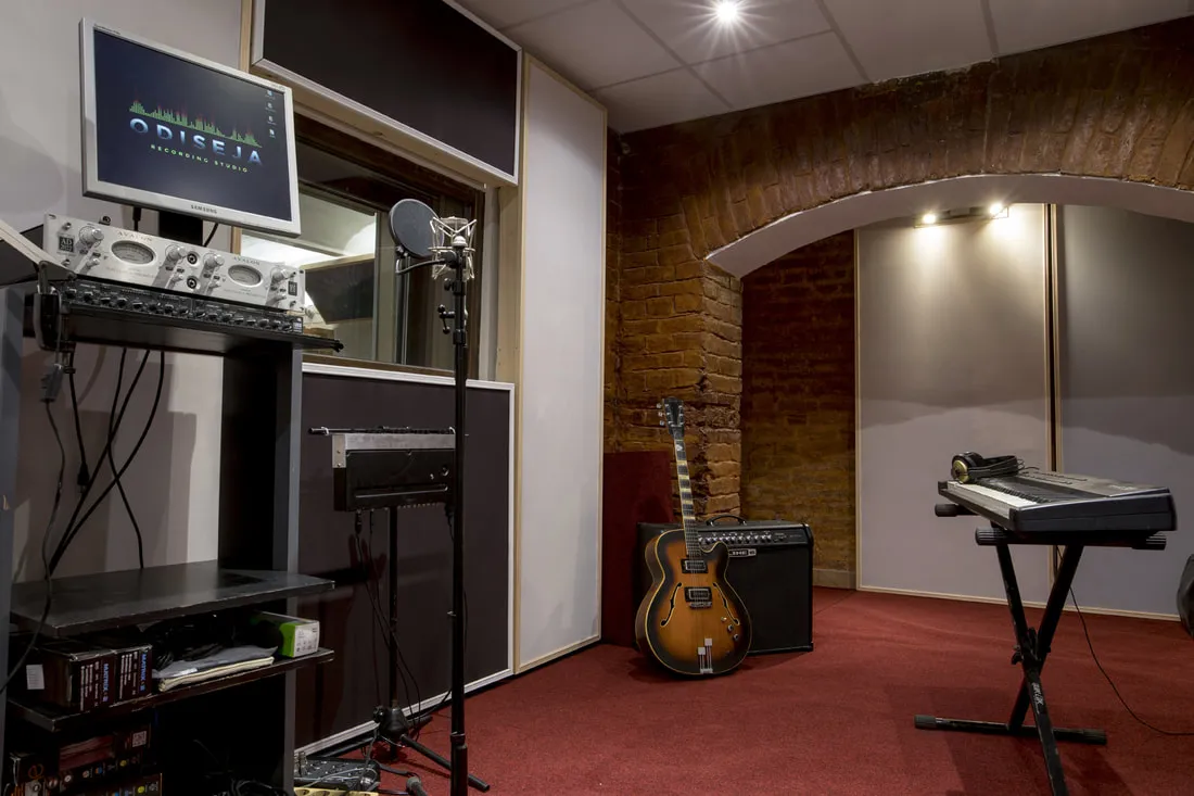 The recording room with microphones, a guitar amp and keyboards