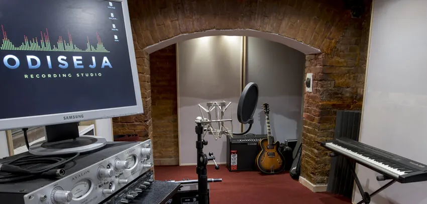 Microphones, guitar and keyboard in the recording room under the brick arch